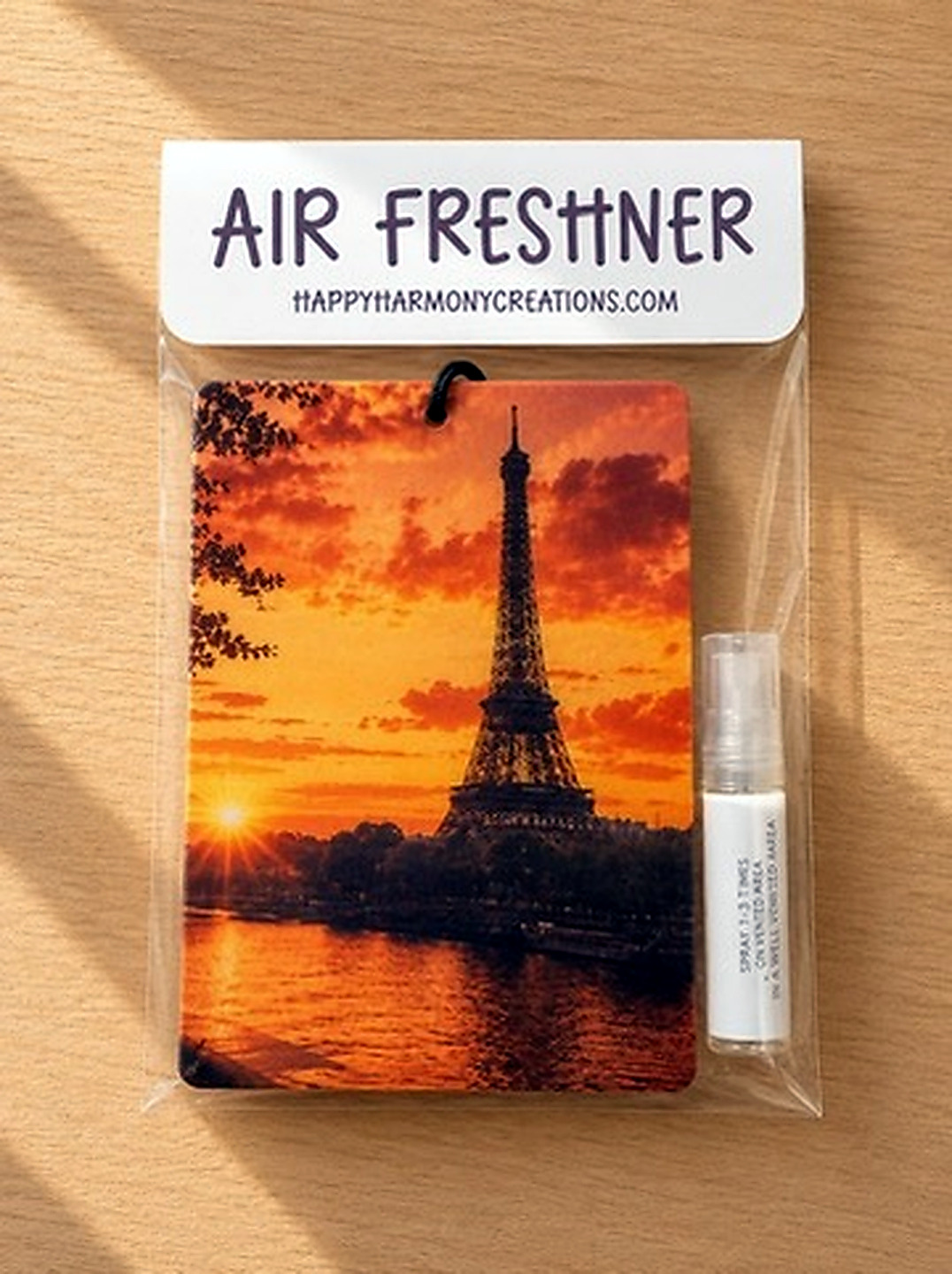 packaged rectangular air freshener with Paris sunset artwork and scent bottle